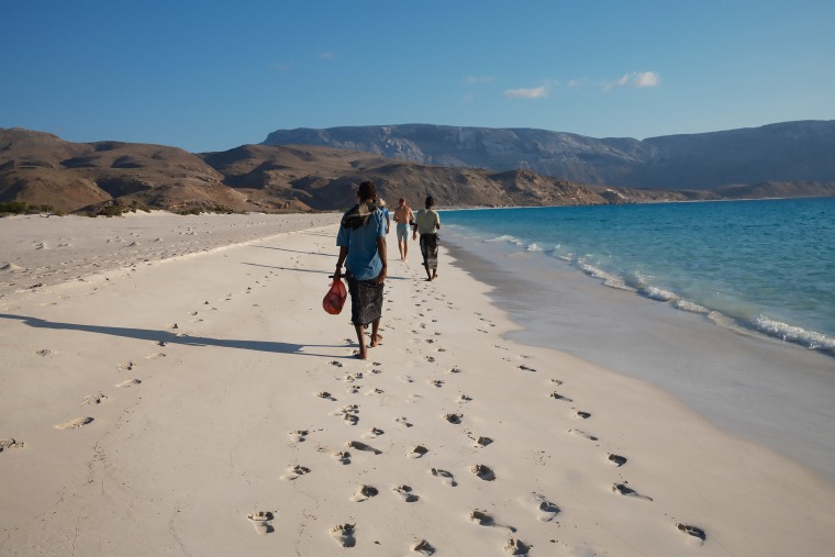 Local guides walk along one of Socotra's white sand beaches with a group of tourists in April.
