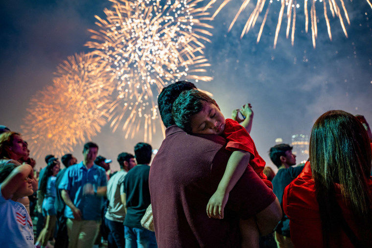 A kid sleeps while the fireworks in the background begin.