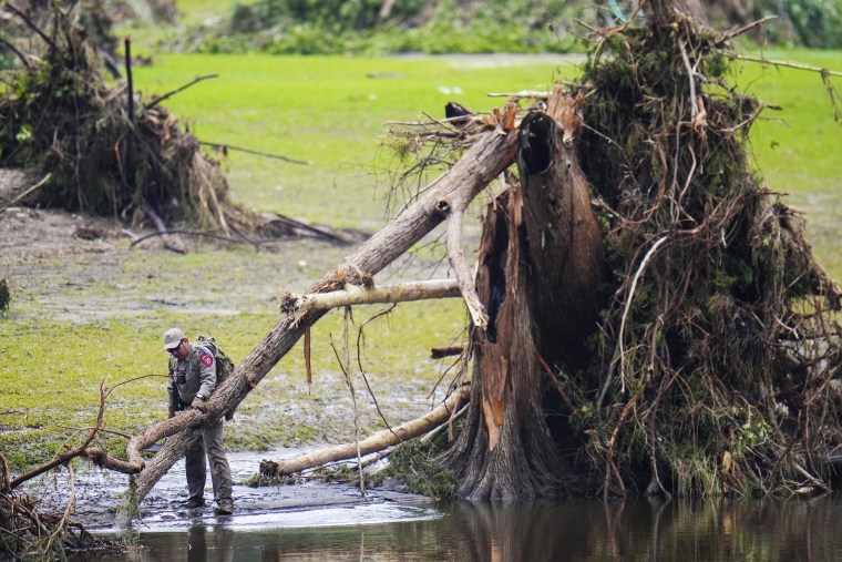 A Texas Department of Public Safety official inspects tree debris at Camp Mystic along the Guadalupe River after a flash flood swept through the area Sunday, July 6, 2025, in Hunt, Texas.