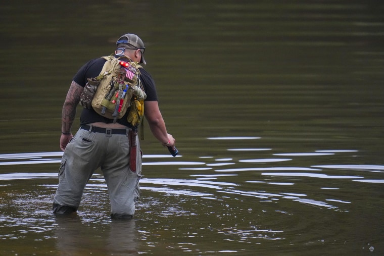 Avi Santos, 23, a civilian from San Antonio, Texas, wades the water at the Guadalupe River as he helps in the recovery effort near Camp Mystic