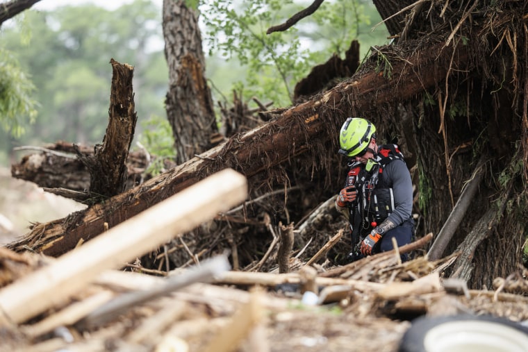 A rescue worker stands amidst debris and fallen trees