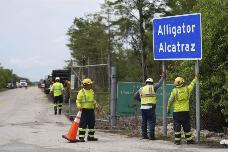 Workers install a sign reading "Alligator Alcatraz" at the entrance to a new migrant detention facility at Dade-Collier Training and Transition facility, Thursday, July 3, 2025, in Ochopee, Fla.