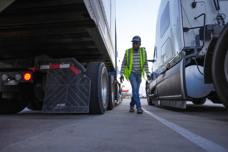 Kevenson Jean walks between two trucks