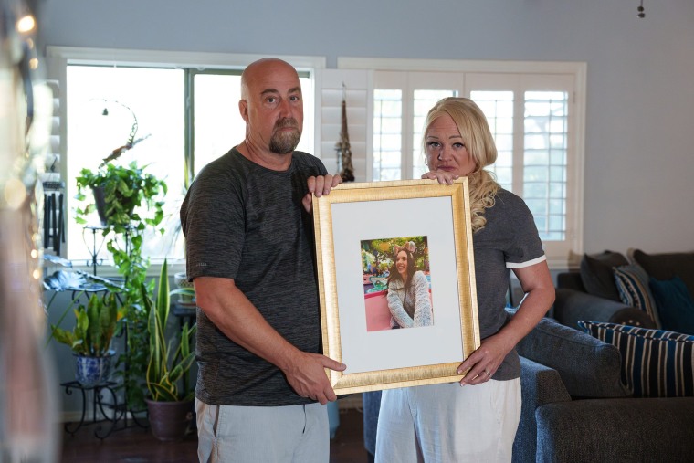 Tom and Erika Pillsbury hold a picture of their late daughter, Mercedes Vega as they pose for a portrait in their living room on