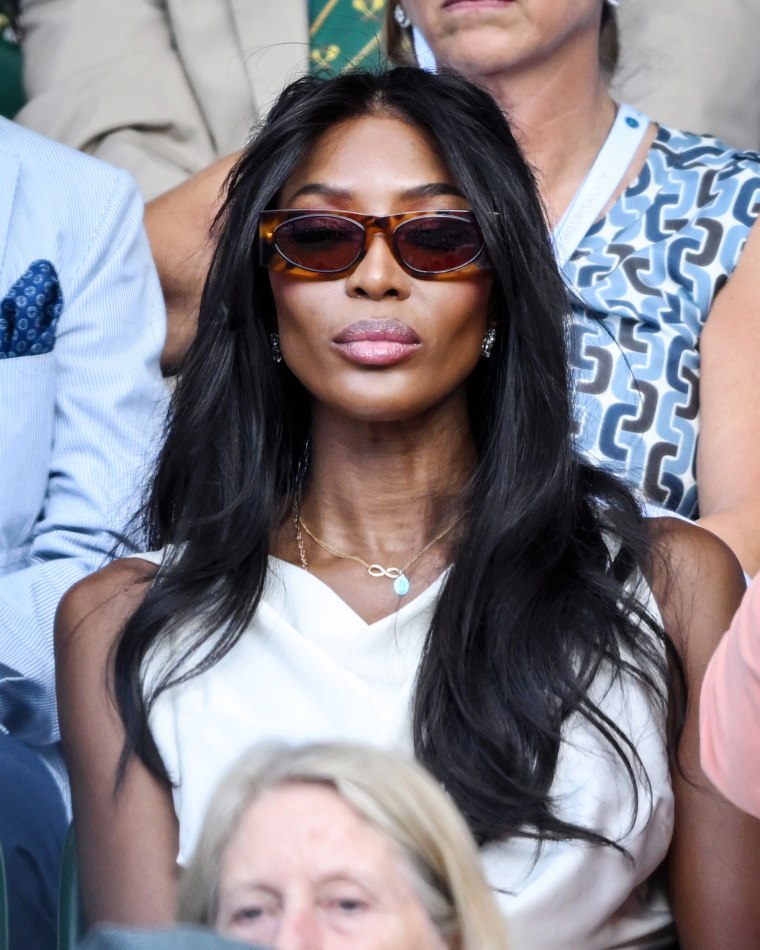 Naomi Campbell sits in an audience outside