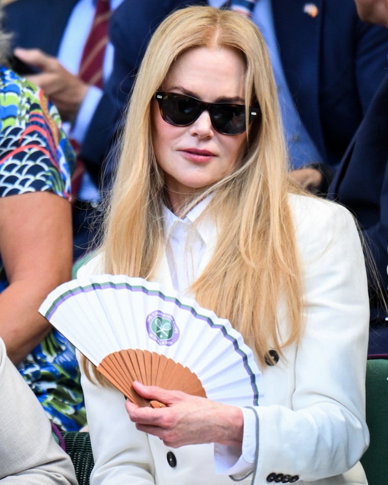 Nicole Kidman fans herself outside while seated in the stands