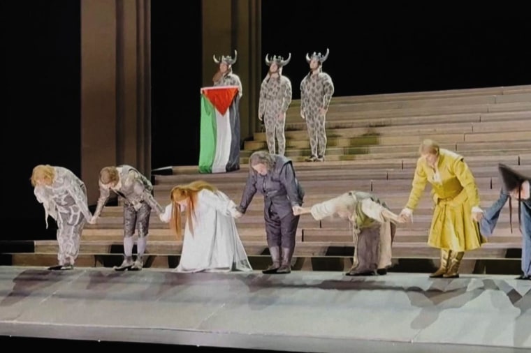 A performer holds a Palestinian flag at the Royal Opera House in London as cast members were taking their bows.