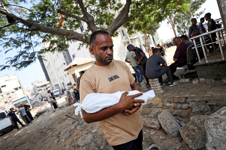 Adham carries the body of his nephew, six-week-old infant Yousef al-Safadi, who died of starvation according to health officials, in Gaza City