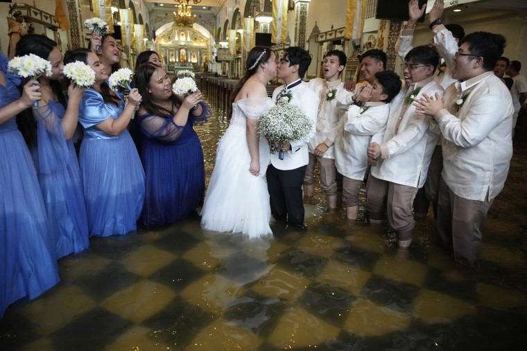 Newlyweds Jade Rick Verdillo, center, and Jamaica pose with a kiss as guests cheer