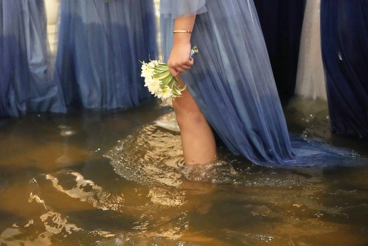 A wedding guest holds a flower during a wedding at the flooded Barasoain church