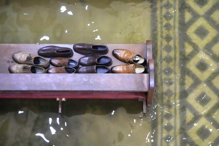 Guests leave their shoes on a pew, above flooded grounds.