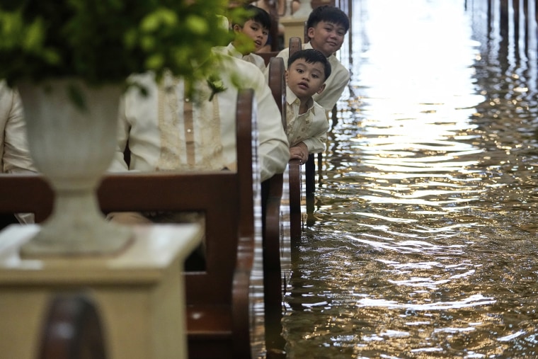 Young boys sit in flooded church pews during wedding