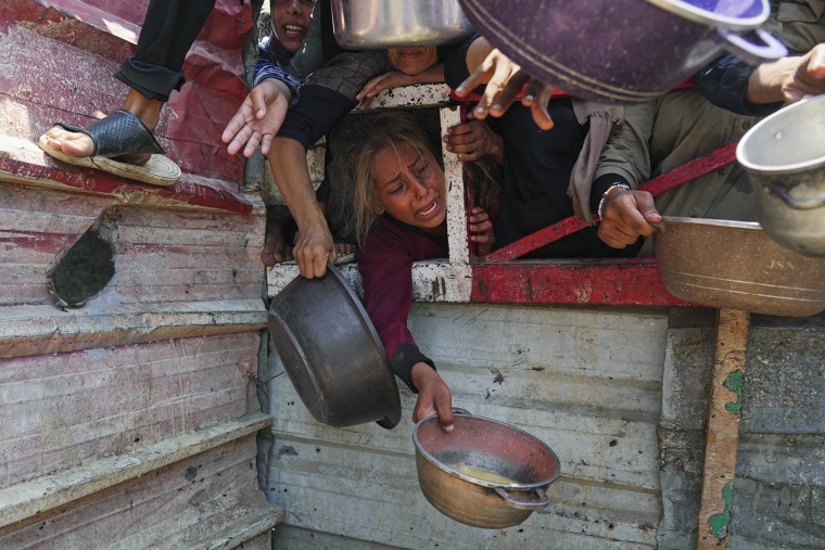Palestinians struggle to get donated food at a community kitchen in Gaza City on Saturday, July 26, 2025. 