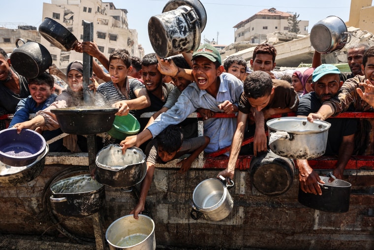 Image: Palestinians crowd at a lentil soup distribution point in Gaza City