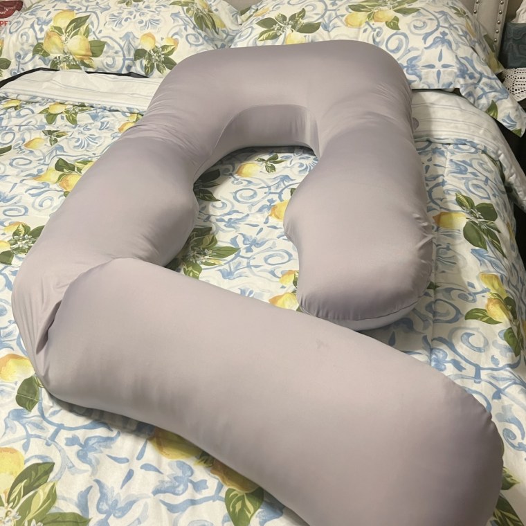 Momcozy U-shaped pillow on top of bedroom comforter