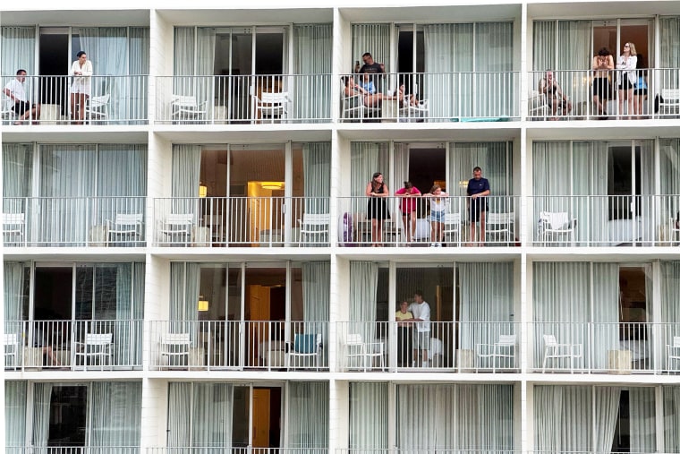 Vacationers stand on balconies at the 'Alohilani Resort looking towards Waikiki Beach after authorities warned of the possibility of tsunami waves