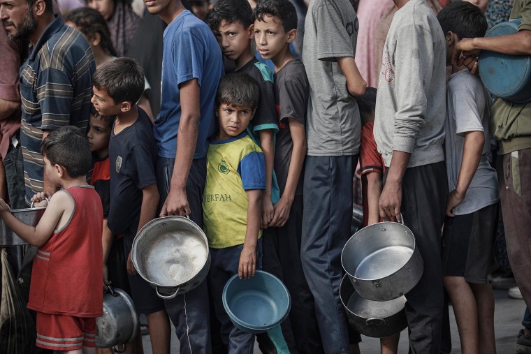 Palestinians form a line to receive hot meals in Gaza