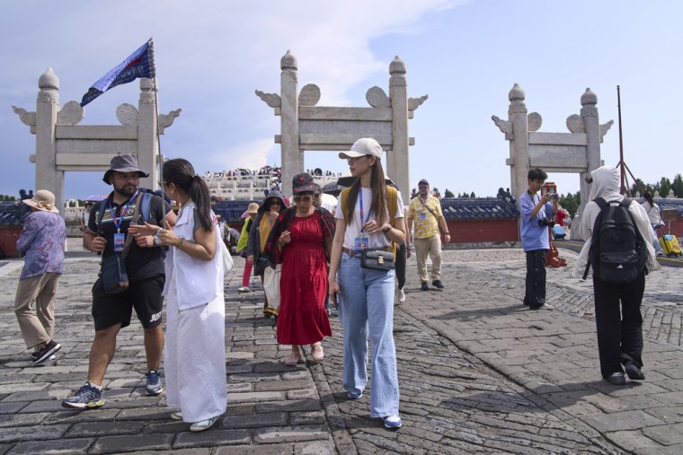 Una guía turística habla con un turista mientras recorren el Templo del Cielo, en Beijing, el 15 de junio de 2025.