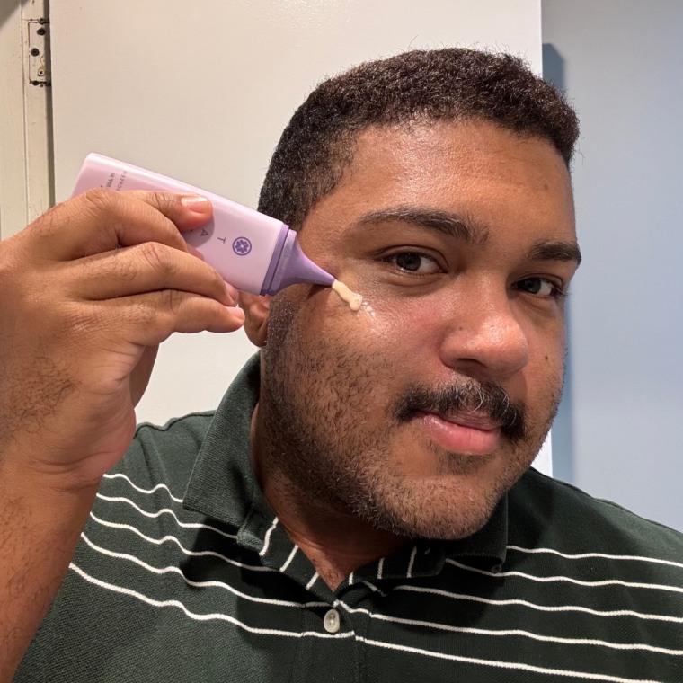 Fernandez in a bathroom, applying the Tatcha Silk Sunscreen to the right side of his face.