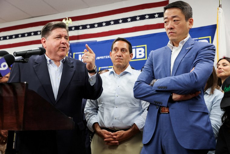 Gov. J.B. Pritzker speaks next to Gene Wu and Trey Martinez