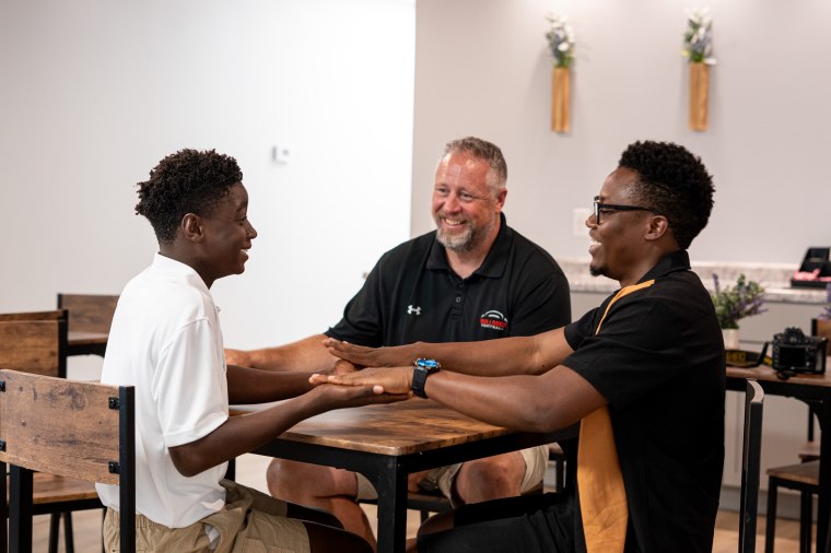 Francion Schafer, 13, thumb wrestles pinch March Rocher and his father, Andy Schafer. 