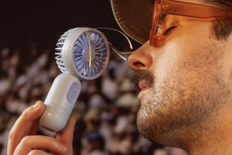 a man holding a portable fan