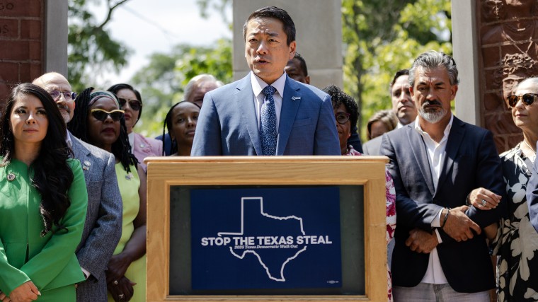 Gene Wu speaks at a podium outside surrounded by other people