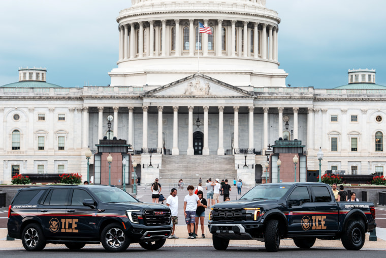 People look at  An Immigration and Customs Enforcement (ICE) branded GMC SUV and an Immigration and Customs Enforcement (ICE) branded Ford pickup truck parked at the Capitol 