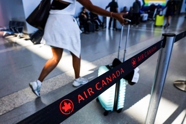 A passenger walk past an Air Canada line rope