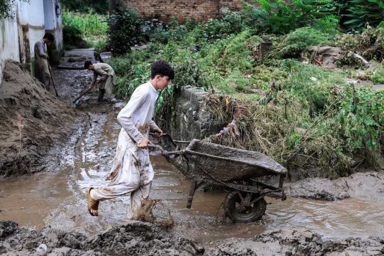 A boy clears mud from a flooded street