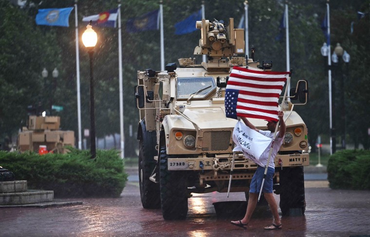 A protester is blown around in the rain as members of the D.C. National Guard take shelter in their vehicle outside Union Station in Washington
