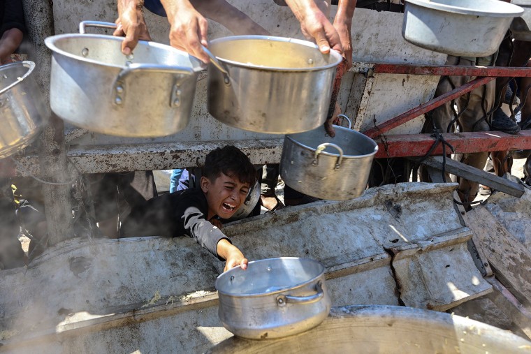 A Palestinian boy extends an quiet cookware to person cooked atom astatine a kindness room successful Gaza City connected Aug. 23, 2025.