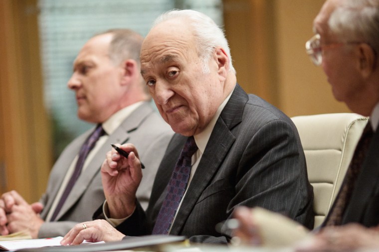 Jerry Adler, center, sits between two people at a table, holding a pen in his hand