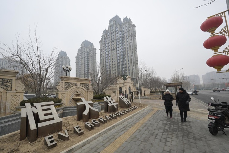 People walk past an Evergrande Group residential complex called Evergrande Palace in Beijing