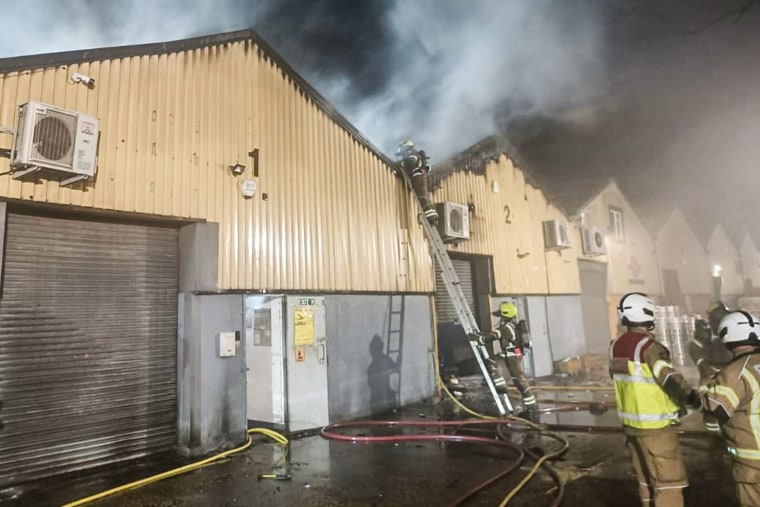 Smoke billows from The Cromwell Industrial Estate building as firefighters surround it