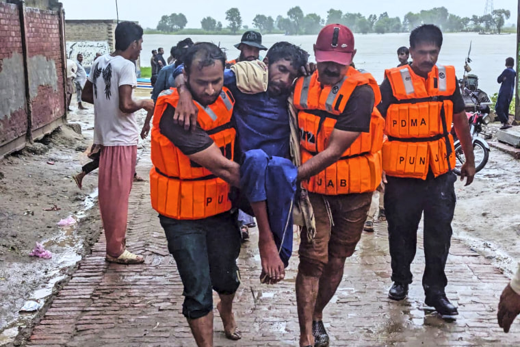 Rescue workers wearing life jackets carry a villager after evacuating him