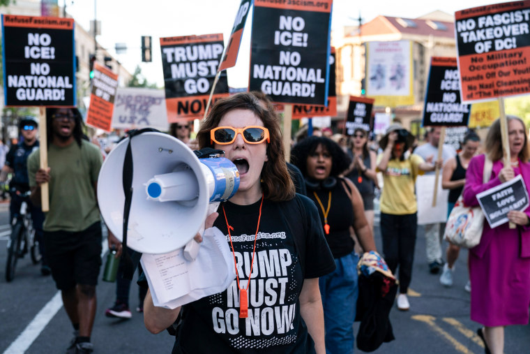 People protest on the street holding signs against Trump and ICE