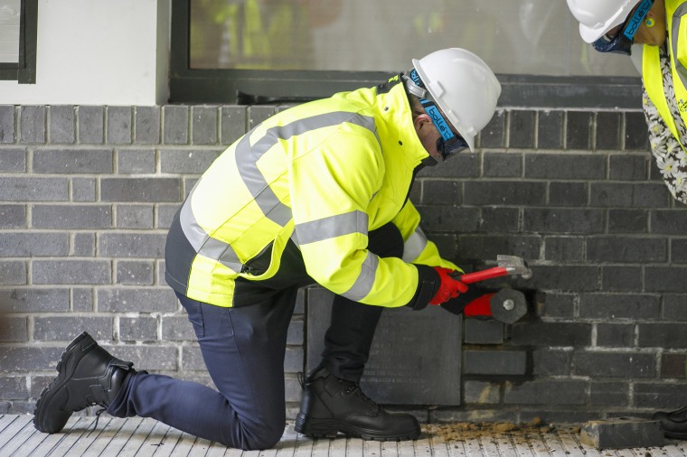 Jason Dawson from the Children's Cancer Centre chiseling the bricks around the time capsule.