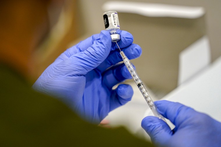 A healthcare worker fills a syringe.