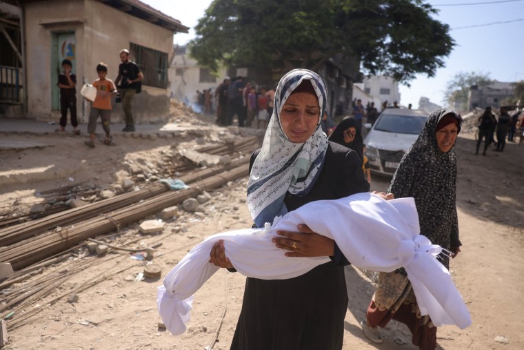 A Palestinian woman carries the body of a child outside Shifa hospital in Gaza City where casualties of Israeli fire were transported ahead of their funerals on Aug. 29, 2025.