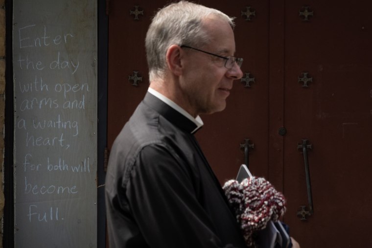 Imagem: grátis. O padre da Igreja Católica de Anchões, Dennis Jehran, fica em frente a uma janela embarcada, carregando uma mensagem de esperança fora de sua igreja em 29 de agosto de 2025.