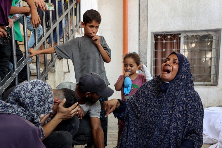 Palestinians mourn over the shrouded bodies of family members killed in an Israeli strike 