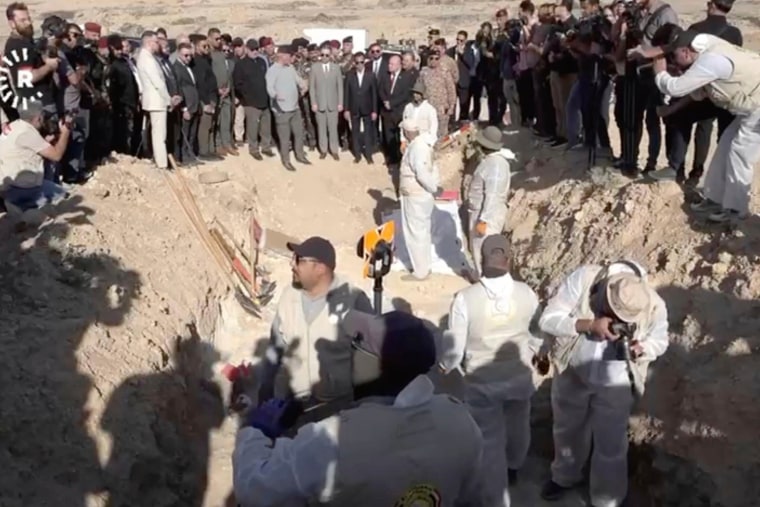 In this image taken from video provided by Rudaw TV, workers dig out human remains at the Khasfa site near the northern Iraqi city of Mosul, where authorities have begun excavating a mass grave believed to contain thousands of victims of the Islamic State.