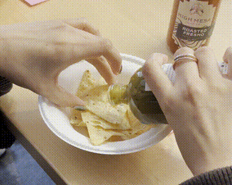 A gif of a hand holding a tortilla chip and pouring High Mesa Co. Roasted Hatch Chili Hot Sauce on top.