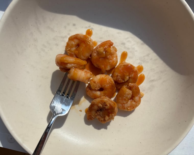 A bowl of shrimp and a fork with shrimp on it, covered in Local Hive Mango Habanero Honey Hot Sauce.
