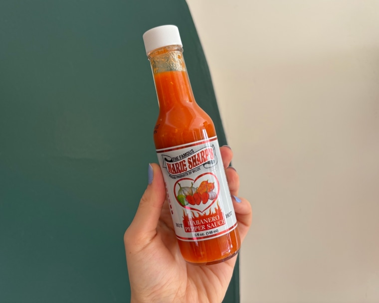 A hand holding a bottle of Marie Sharp’s Original Hot Habanero Pepper Sauce.