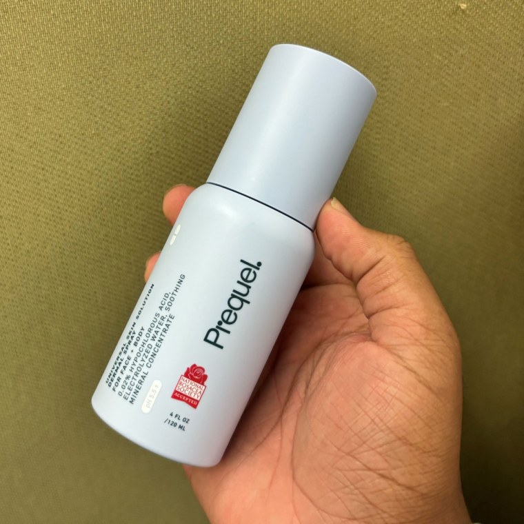 Person holding Prequel Universal Skin Solution Dermal Spray in hand.