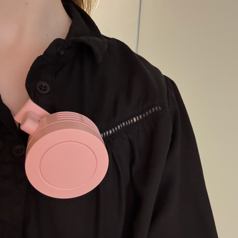 Portable mini fan clipped on a shirt.