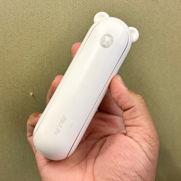 Person holding white Jisulife handheld fan in right hand.