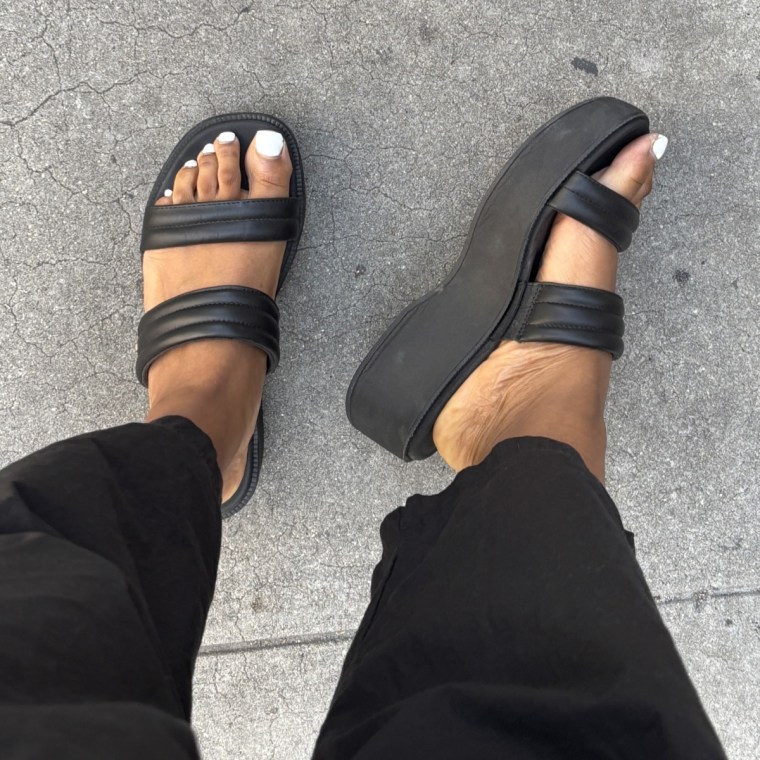 The Reef Lofty Lux Hi Sandals in black, worn by Morris, against a pavement sidewalk background.